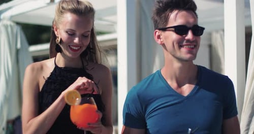 Couple drinking cocktails by the pool at luxury resort