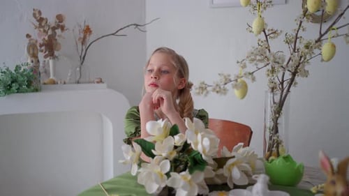 Thoughtful Girl in Green Dress Sitting at Easter Decorated Table Spring Interior with Flowers and