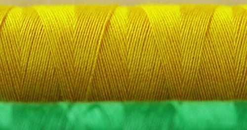 Macro shot of colorful rolls with sewing thread fabrics. The rolls come in all colors and shades w