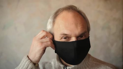 Portrait of mature man, take off a black face mask. End of pandemic, Coronavirus.