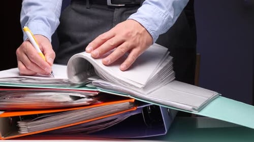 Business Person Organizing Documents and Writing Paperwork