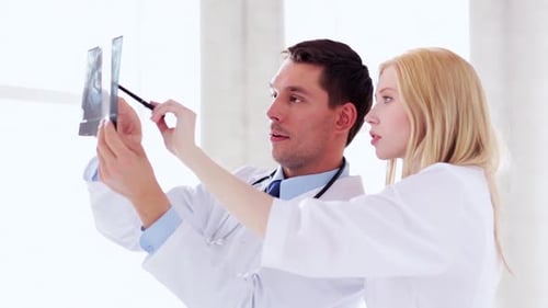 Doctors analyzing x-ray prints in hospital discussing patient diagnosis