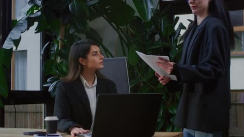 Two Businesswoman Working Together Using Laptop Pc Sitting at Table and Discussing a Project