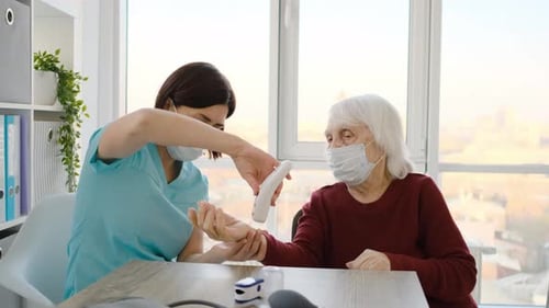 Health Worker Applying Lotion to Senior Woman's Hand
