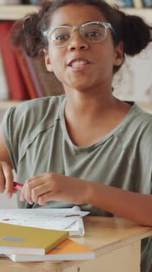 Black Girl Raising Arm and Asking Question during Lesson at School