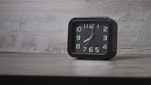 The Pointer Clock on a Wooden Table Shows the Time