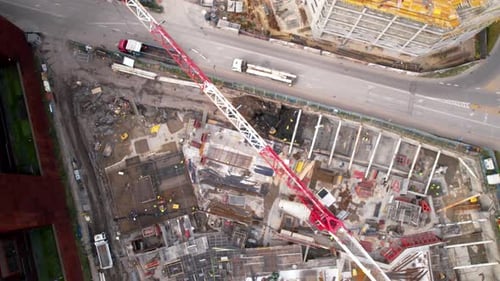 Bird's-eye view of a bustling construction site with towering cranes, machinery, and a city street a