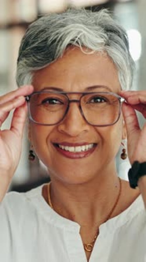 Smiling Woman Putting on Eyeglasses in Home Interior