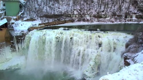 Schönheit eines Stromfalls, der über eisige Klippen in einer atemberaubenden Winterlandschaft, umgeben von Schneewald, stürzt