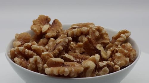 Bowl of Shelled Walnuts Rotating on White Background