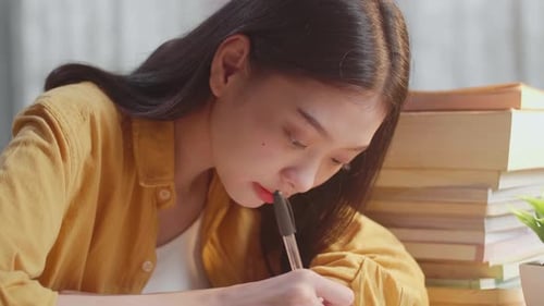 Close Up Of Young Asian Female Writing On The Book While Studying At Home