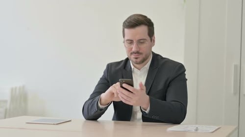 Businessman Browsing Internet on Smartphone in Office