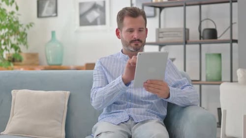 Man Sitting on Couch Using Tablet Device