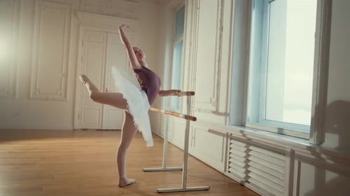 Graceful Ballerina Practices Ballet at Barre in Studio