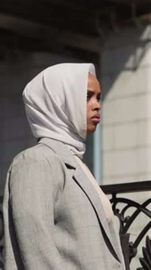 Sad Arabian Woman Stands By Fence on Town Embankment