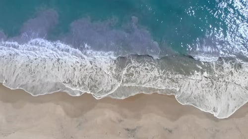 Aerial View Of Waves Crashing On sandy Beach during beautiful summer day
