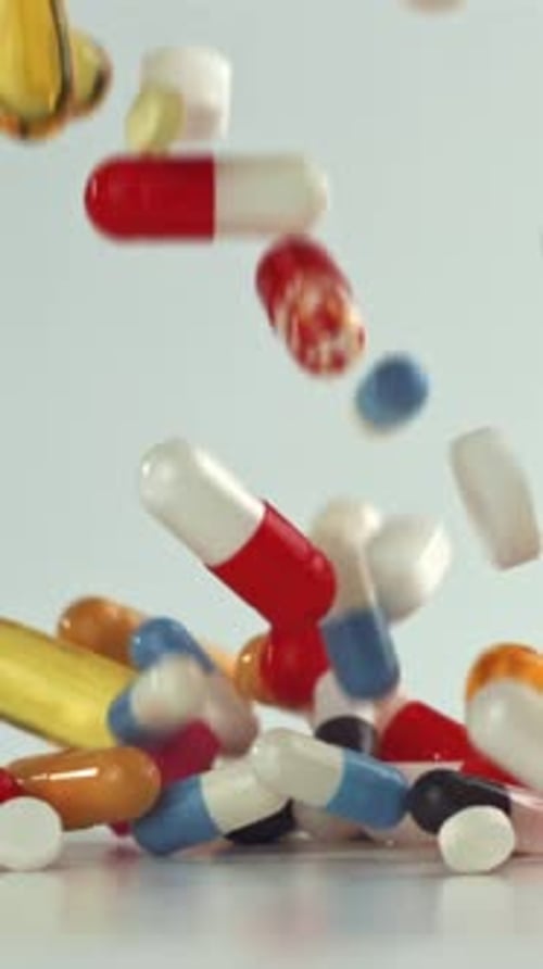 Vitamines multicolores pleuvant sur une surface blanche éclatante filmées par une caméra haute vitesse à 1000 images par seconde