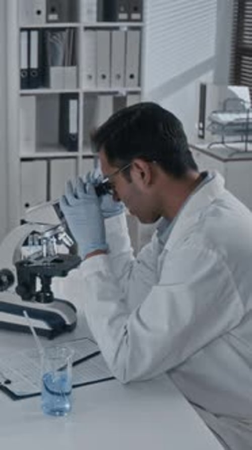 Scientist Uses Microscope In Bright Laboratory