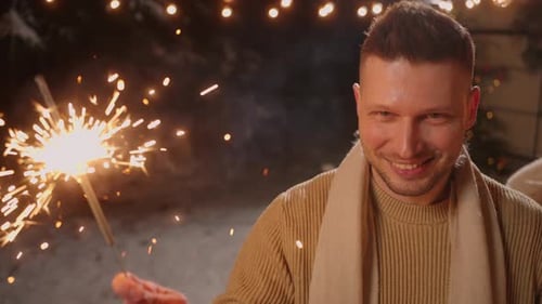 Man Smiles and Holds Sparkler at Christmas