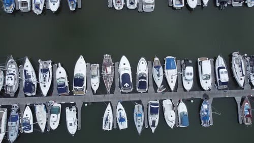 Top down aerial drone view above luxury moored private marina sailing ships and yacht boats dolly le