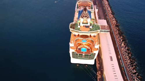 Flight over the huge long modern cruise ship standing at the pier.