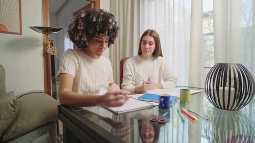 Two Young Women Collaborate at a Glass Table