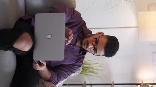Young Adult Opening Laptop on Couch Indoors