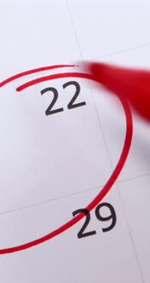 Portrait video footage of calendar showing the number 22 with a males hand circling the date