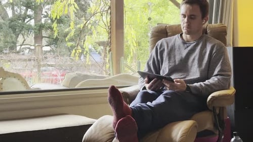 Man Relaxing at Home Using Tablet Device