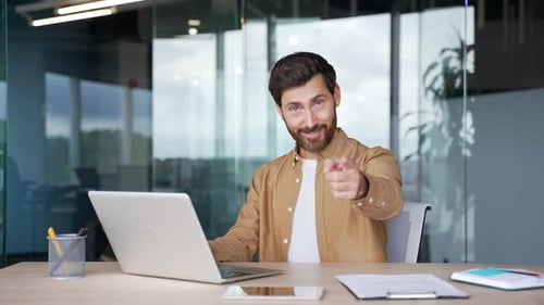 Confident businessman asks to join him, beckons with inviting hand gesture sitting at laptop at work