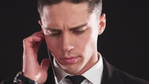 Intense Closeup of a Handsome Man Listening Intently Through His Earpiece