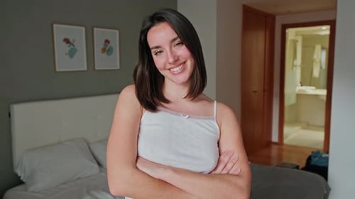 Woman Smiling in Bedroom with Arms Crossed