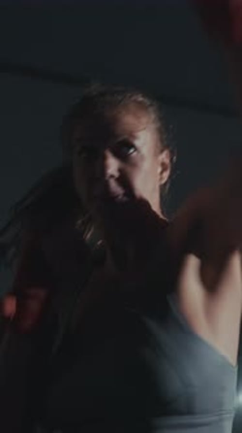 Séance d'entraînement intense mettant en vedette un boxeur pratiquant des techniques dans une salle de sport faiblement éclairée