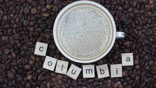Top View of a Cup of Coffee on a Background Coffee Beans with the Inscription Columbia