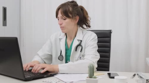 Professional Doctor Typing On Her Laptop Computer On The Table In Medical Clinic. medium shot, zoom-