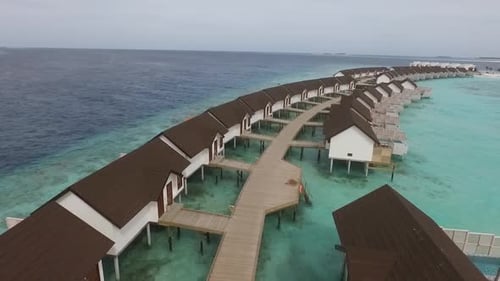 Drone atirou em vilas acima da água com beco de madeira em um resort nas Maldivas. Água azul e turquesa. Completo