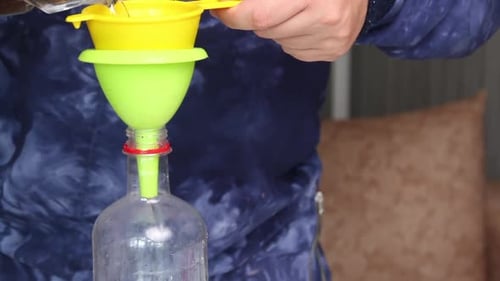 Um homem derrama vodka com infusão de lavanda de um decantador em uma garrafa.
