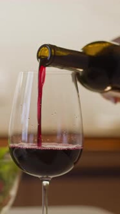 Frau füllt Weinglas mit Rotwein und serviert romantisches Abendessen