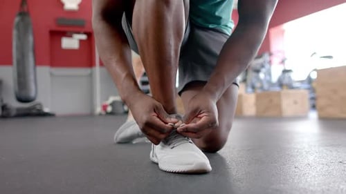 African American man ties his sneakers at the gym