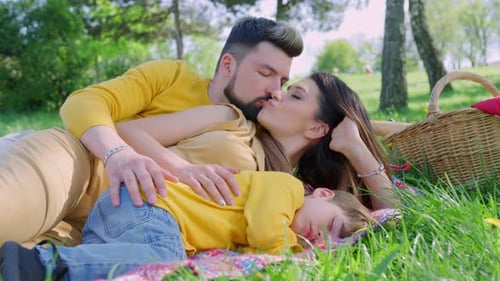 Romantic Couple Kissing Near Sleeping Child at Picnic