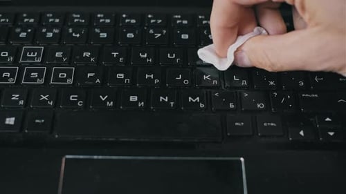 Cleaning a Black Laptop Keyboard with a Wipe