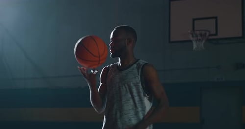 Young Adult Spins Basketball on Finger in Gym