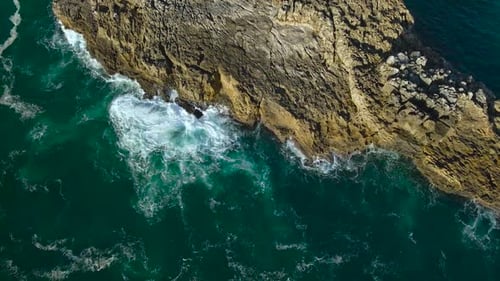 Aerial Drone View Of Emerald Ocean Waves Hitting Rugged Rocks