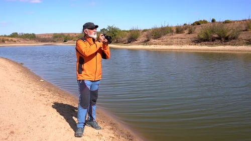 Man Photographs Still Lake On Bright Sunny Day