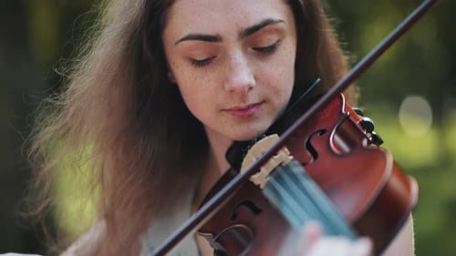 A Young Girl Plays the Violin in the City Park
