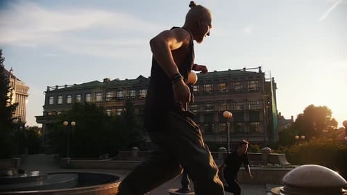 Men Performing Parkour Stunts in City Park at Sunset