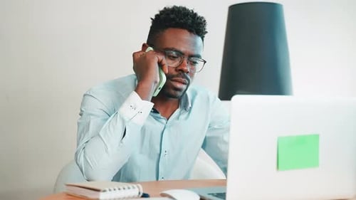 Man Working on Laptop Calling on Phone
