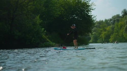 Athletic Young Adult Man Practicing Paddle Boarding In River In Summer Standup Paddleboarding