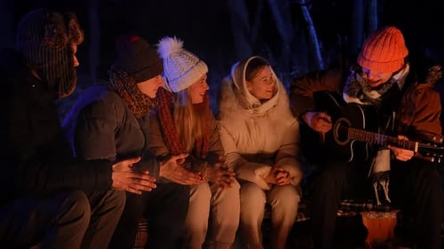 Friends Sitting Around a Campfire in the Woods on a Winter Evening