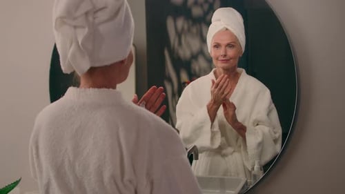 Senior Woman Applying Lotion in Bathroom Mirror